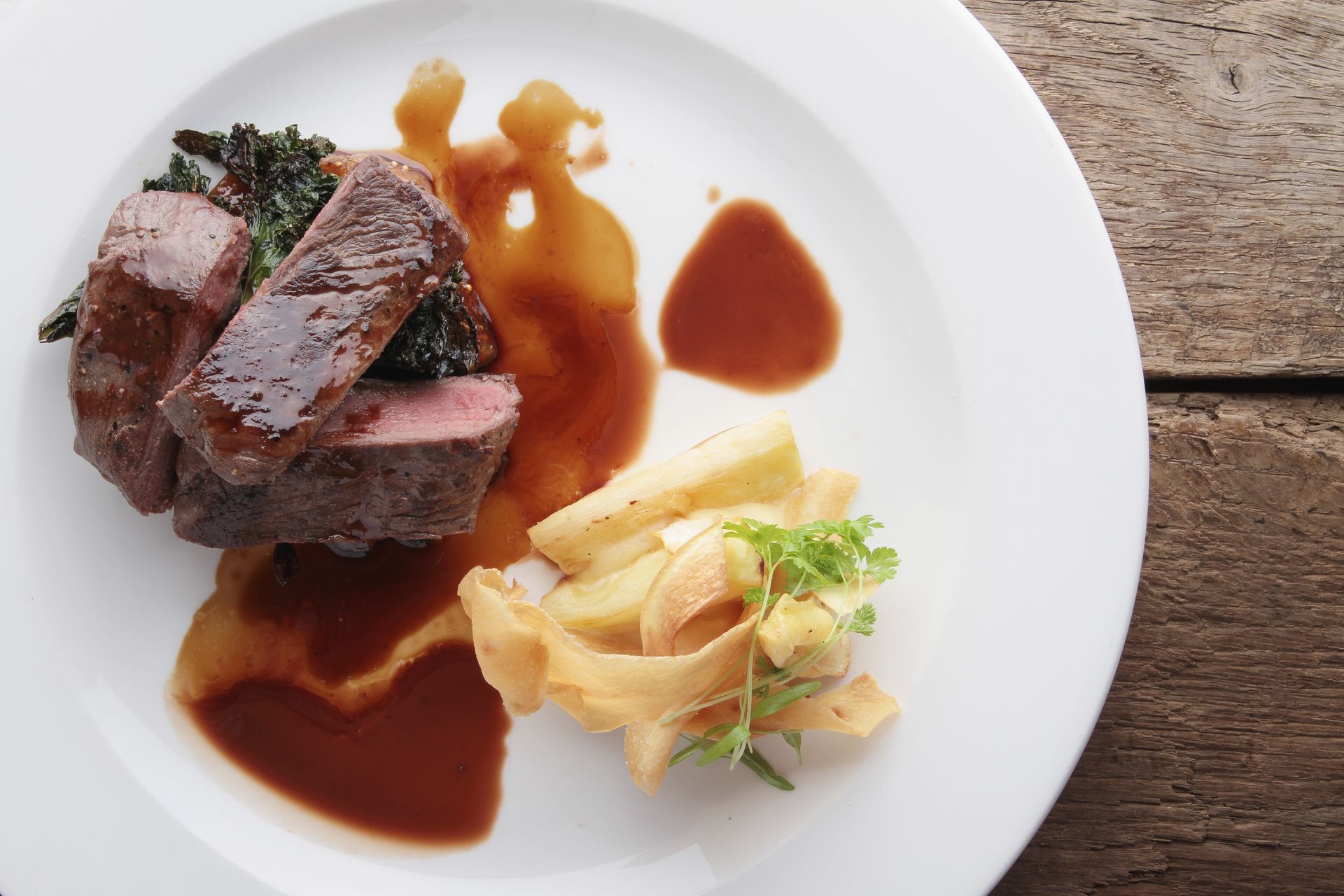 Ein weißer Teller mit Fleisch und Pommes Frites