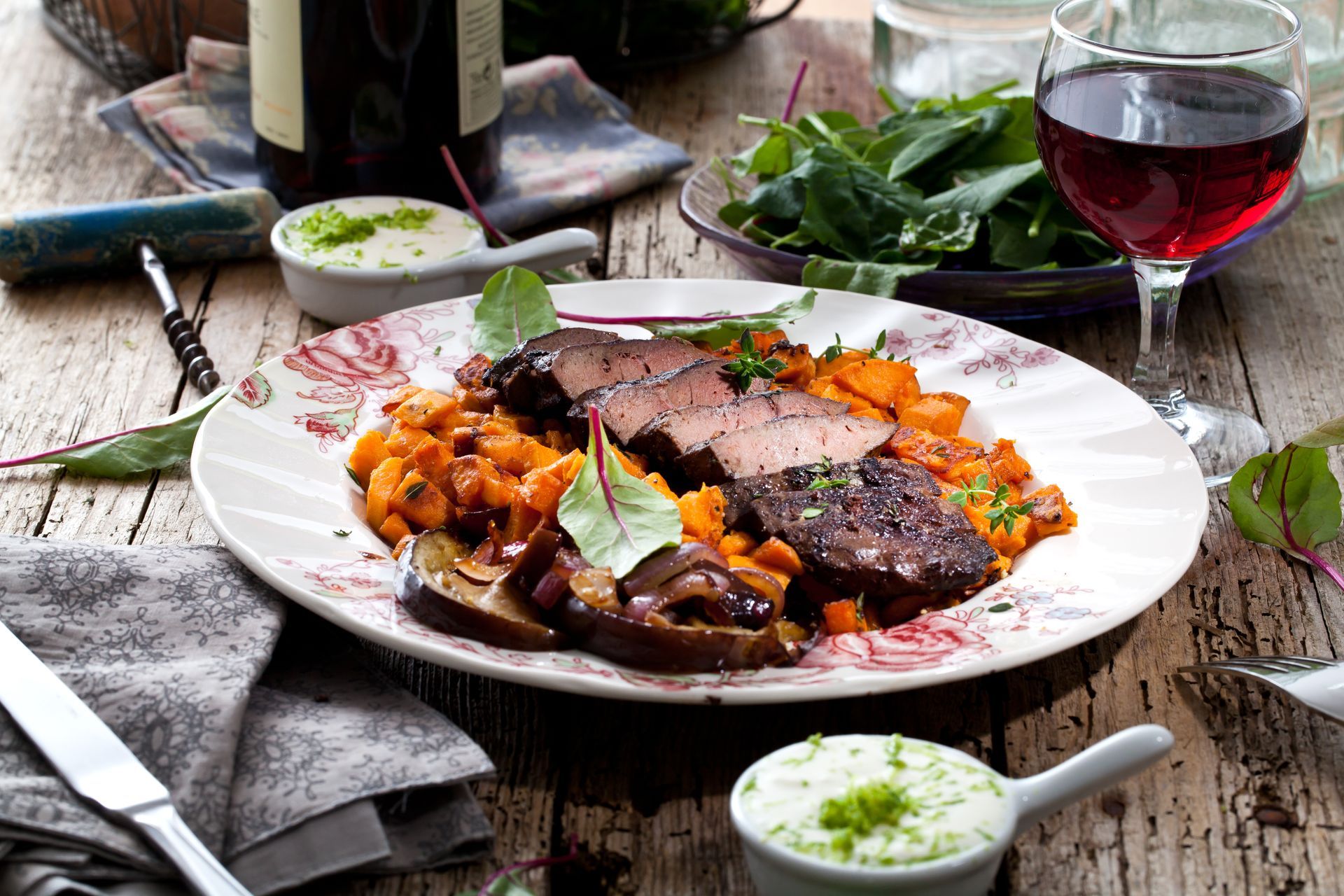 Ein Teller mit Essen und ein Glas Wein auf einem Holztisch.