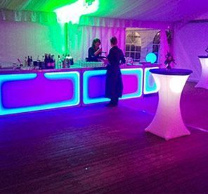 Eine Frau steht an einer Bar mit violettem und grünem Licht.