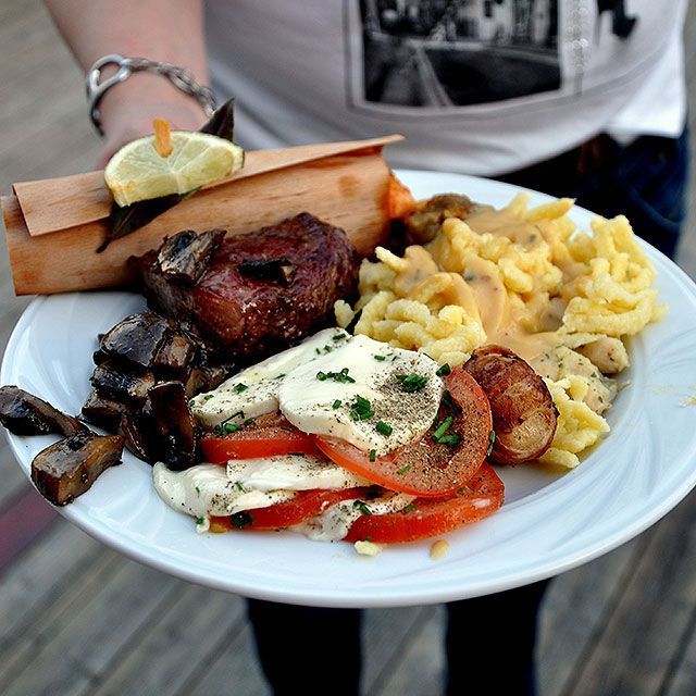 Eine Person hält einen Teller mit Essen mit Fleisch und Gemüse