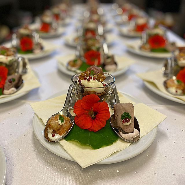 Ein Teller mit Essen, Löffeln und Blumen auf einer Serviette auf einem Tisch.