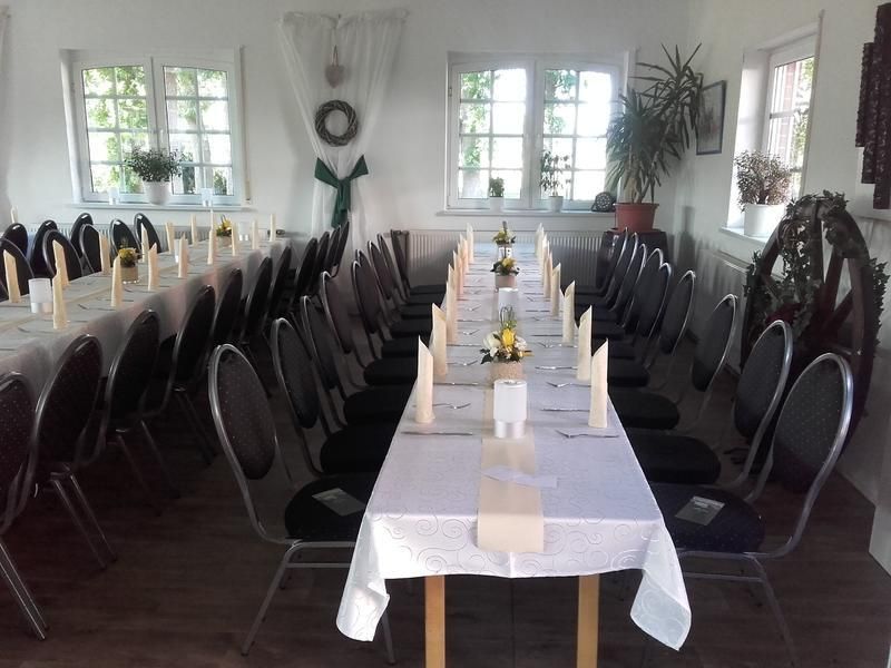 Ein langer Tisch mit weißer Tischdecke und schwarzen Stühlen