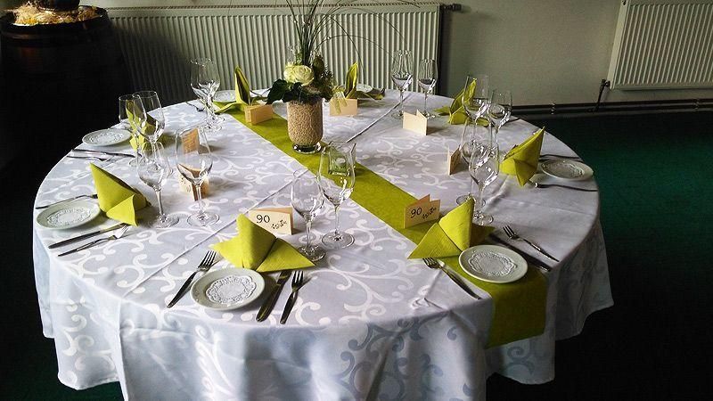 Ein runder Tisch mit Tellern, Besteck und einer Vase mit Blumen darauf.