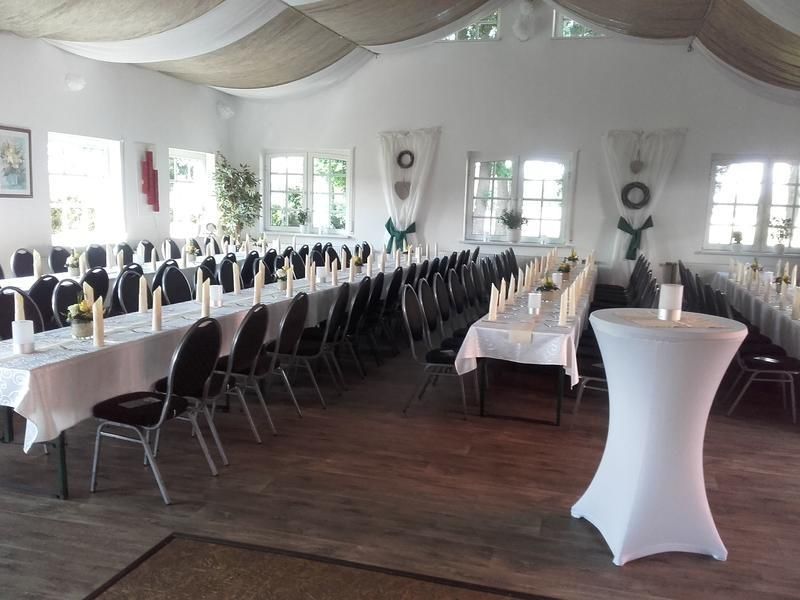 Ein großer Raum mit Tischen und Stühlen für einen Hochzeitsempfang