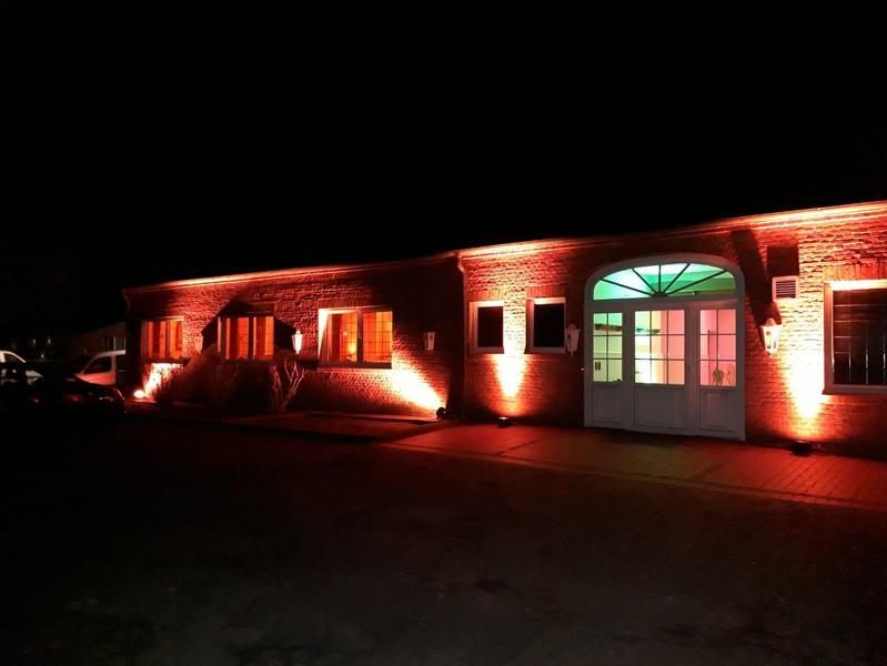 Ein Backsteingebäude wird nachts mit roten Lichtern beleuchtet.
