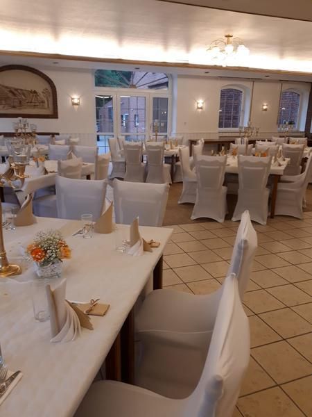 Ein großer Raum mit Tischen und Stühlen für einen Hochzeitsempfang