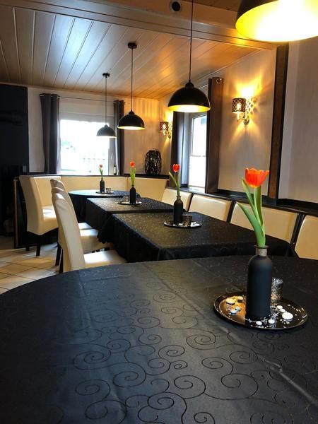 Ein Restaurant mit Tischen und Stühlen und einer Vase mit Blumen auf dem Tisch