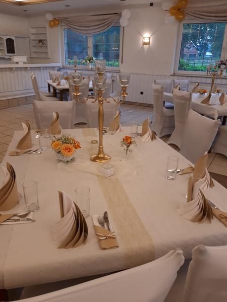 Ein großer Raum mit Tischen und Stühlen, aufgestellt für einen Hochzeitsempfang.