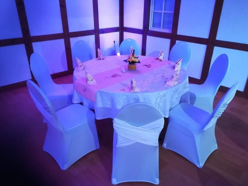 Ein runder Tisch mit weißer Tischdecke und blauen Stühlen