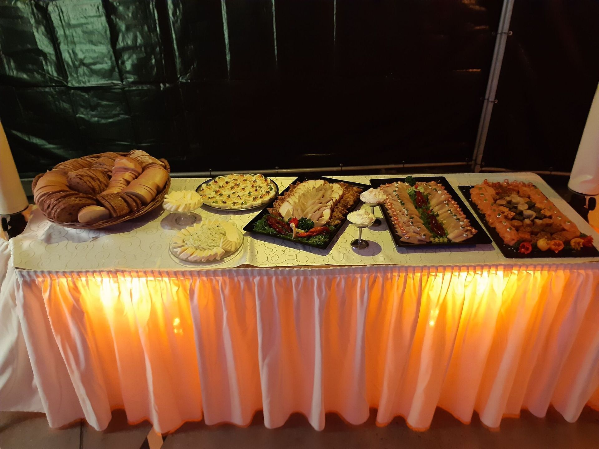 Ein Tisch mit einer weißen Tischdecke und einem Haufen Essen darauf