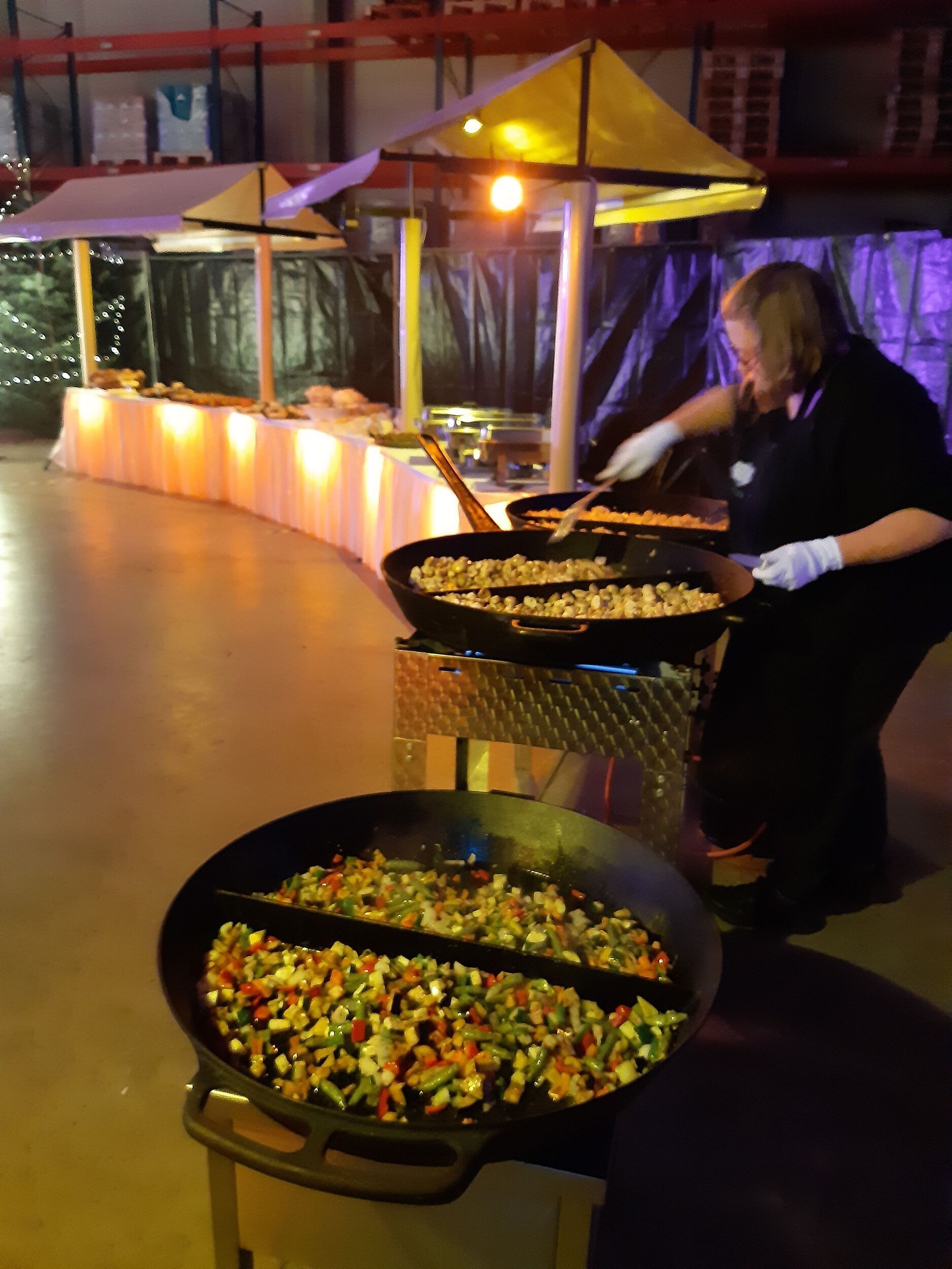 Eine Frau kocht Gemüse in einer großen Pfanne