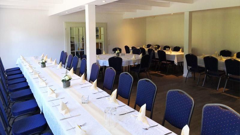 Ein langer Tisch in einem Raum mit blauen Stühlen
