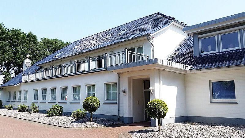Ein großes weißes Gebäude mit einem schwarzen Dach und vielen Fenstern