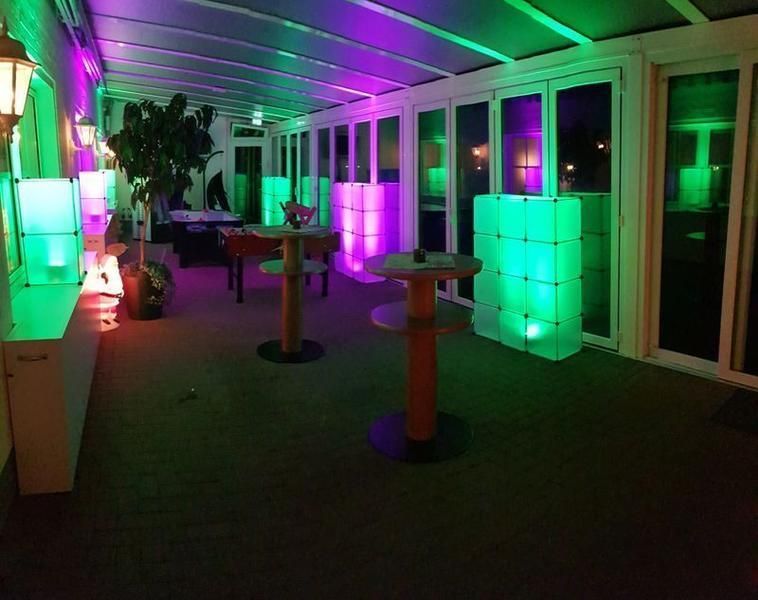 Ein Raum mit Tischen und Stühlen, die mit grünem und violettem Licht beleuchtet sind.