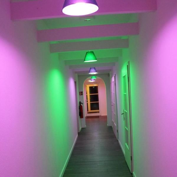 Ein langer Flur mit rosa und grünen Wänden und Lichtern an der Decke.