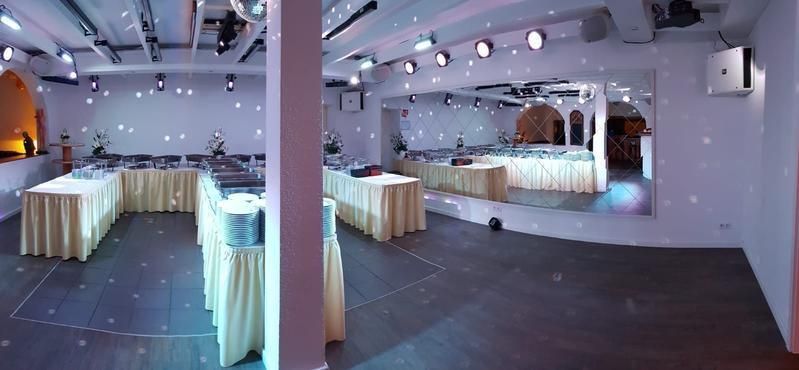 Ein großer Raum mit Tischen und Stühlen, die für eine Party aufgestellt sind.