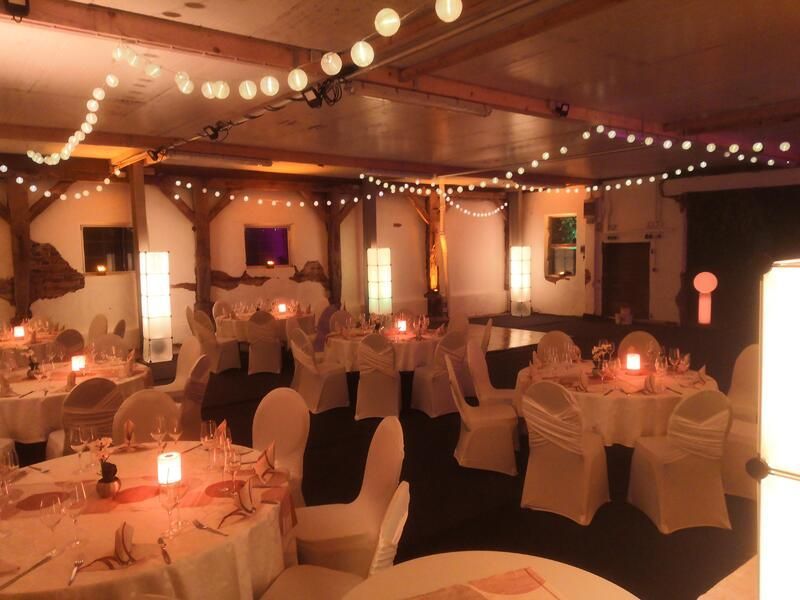 Ein großer Raum mit Tischen und Stühlen für einen Hochzeitsempfang