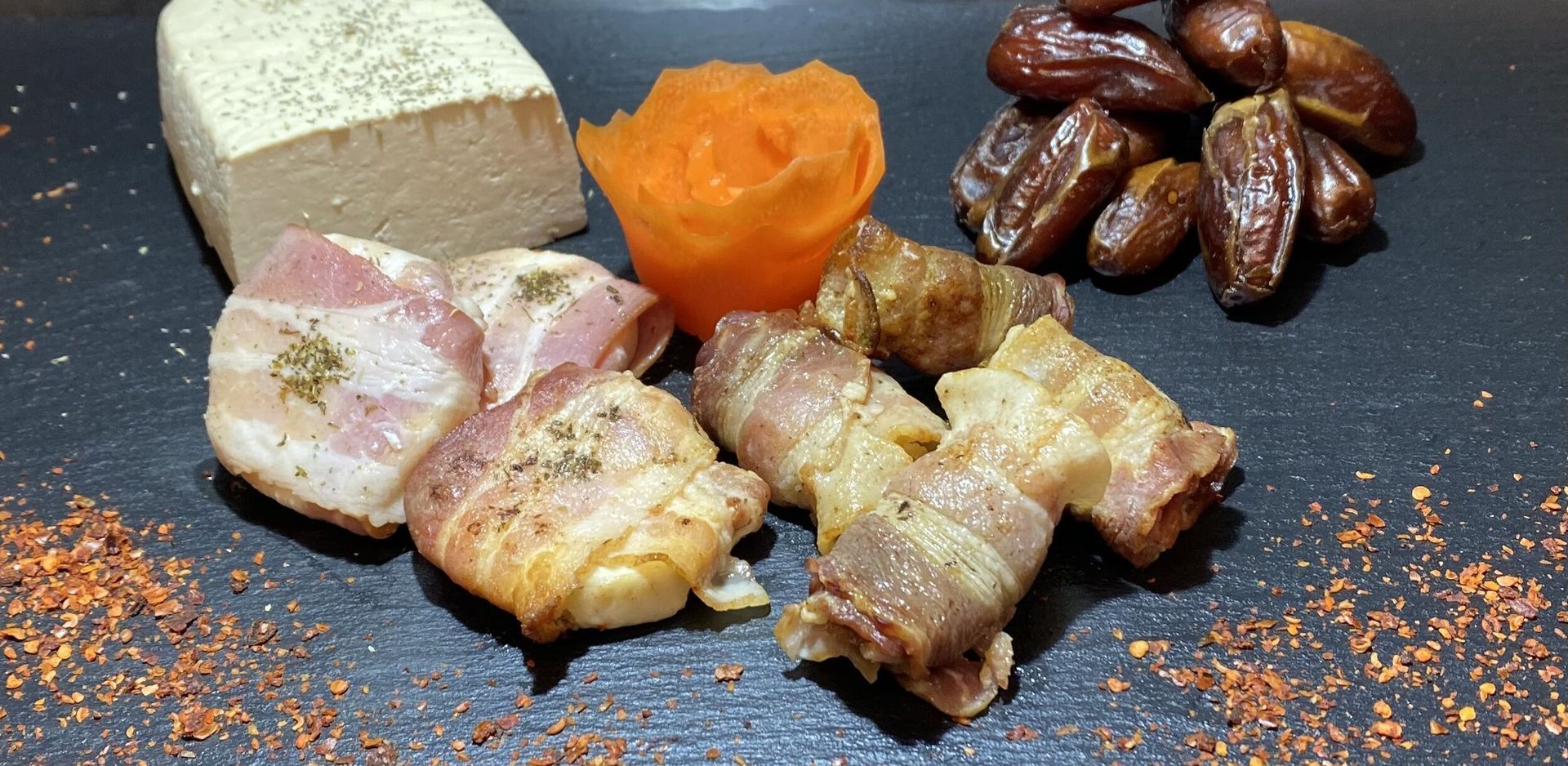 Ein Teller mit Essen mit Speck und Datteln darauf