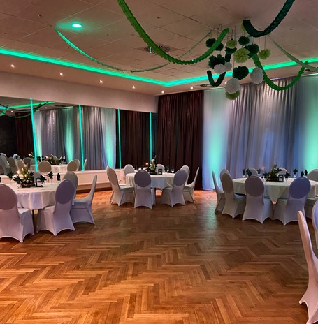 Ein großer Raum mit Tischen und Stühlen, aufgestellt für einen Hochzeitsempfang.