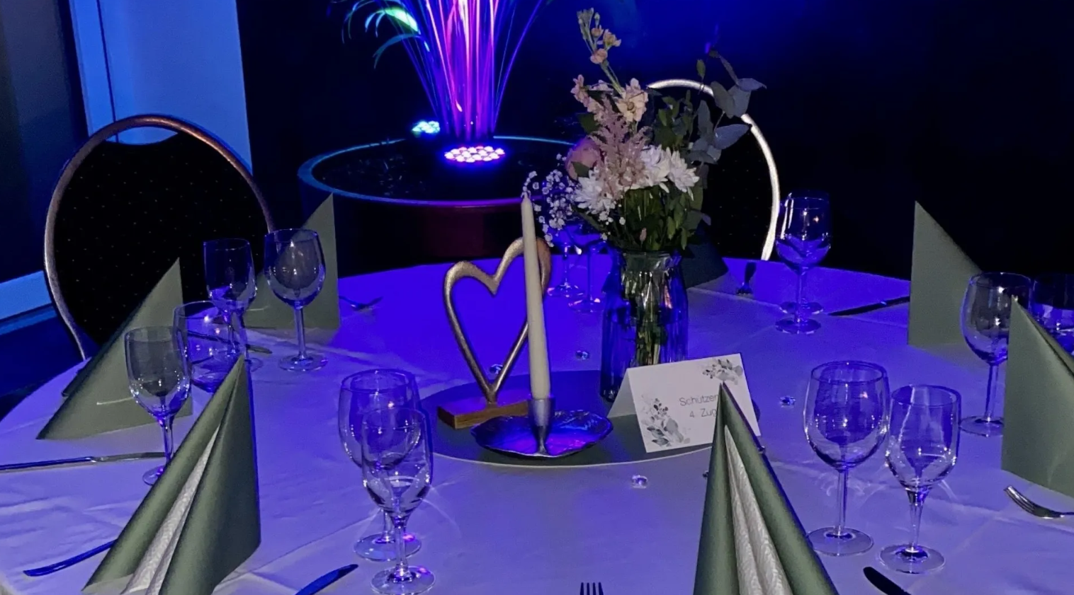 Ein für einen Hochzeitsempfang gedeckter Tisch mit einer Vase mit Blumen darauf.