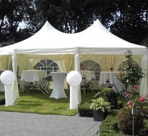 Ein großes weißes Zelt mit Tischen und Stühlen darin.