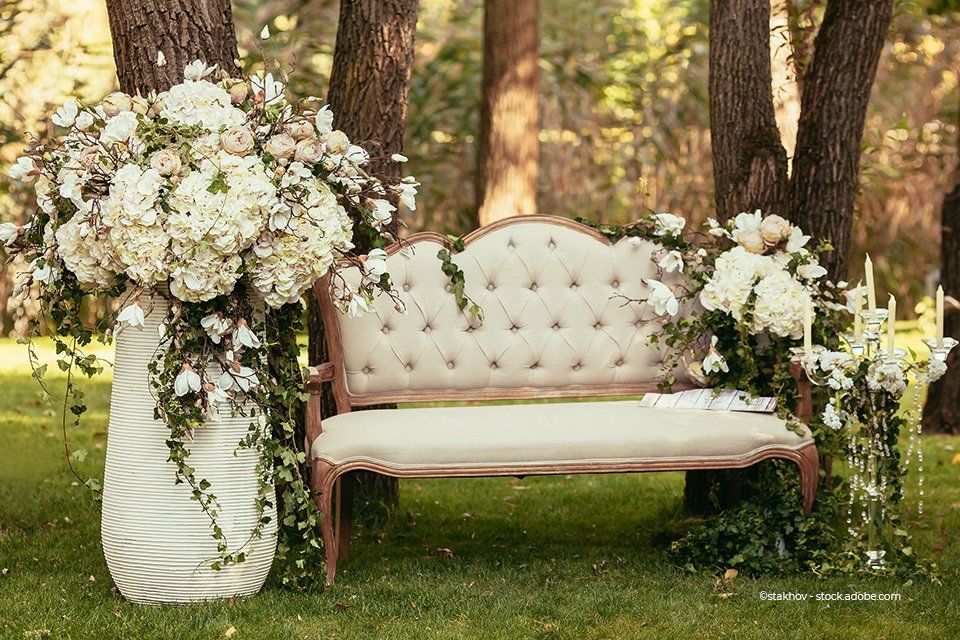 Gartenbau Bunk – eine Sitzbank im Freien, dekoriert mit weißen Rosen
