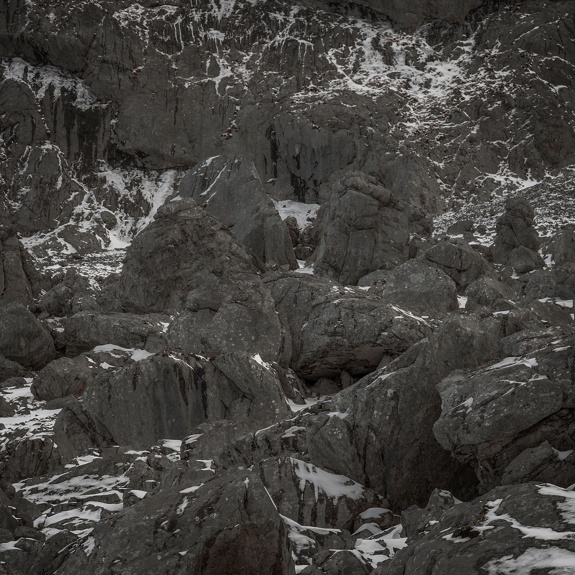 Rocas montañosas grises y dentadas con parches de nieve.