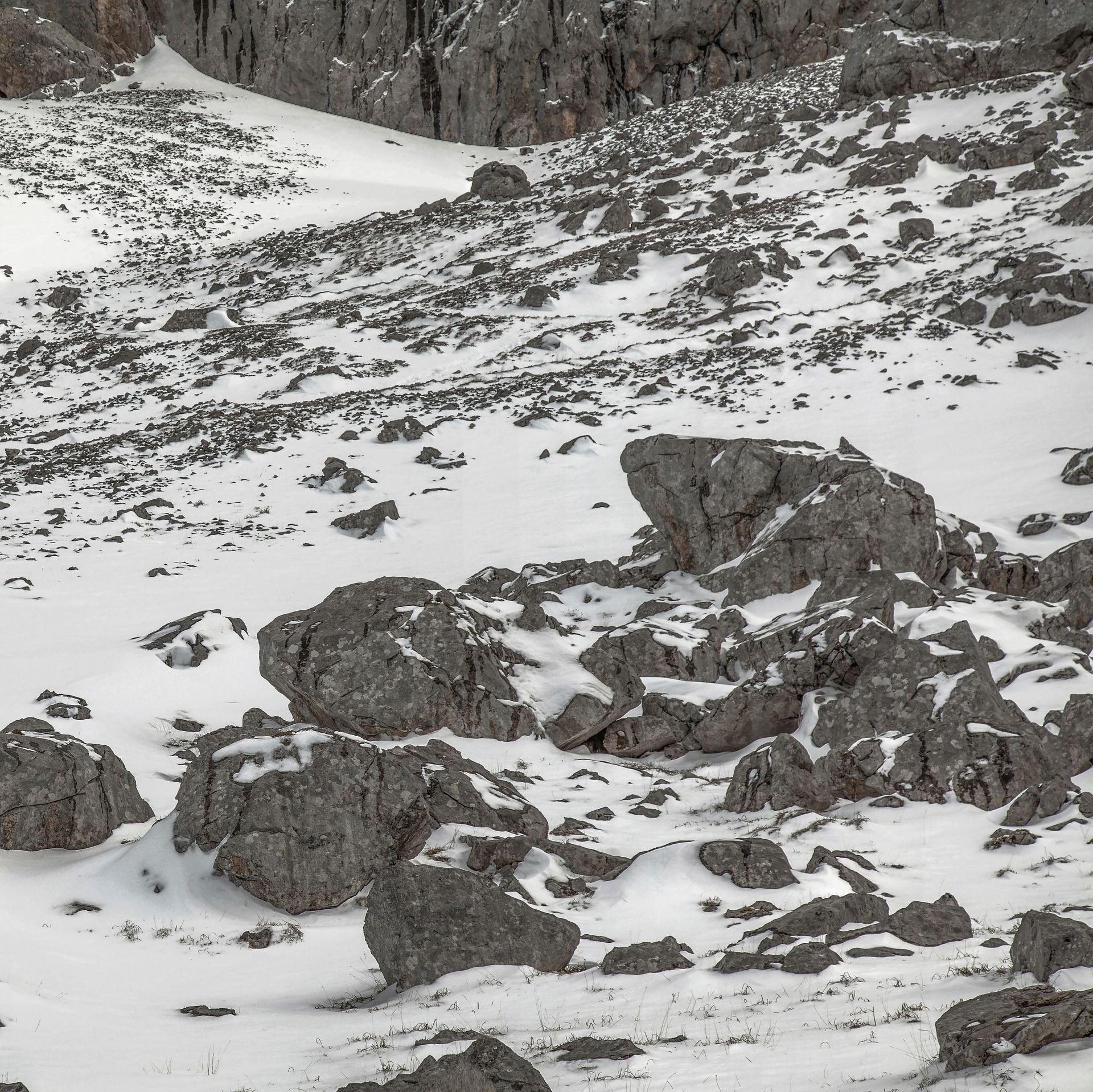 Paisaje de montaña nevada con rocas y parches de nieve.