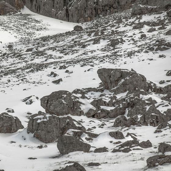 Paisaje de montaña nevada con rocas y parches de nieve.