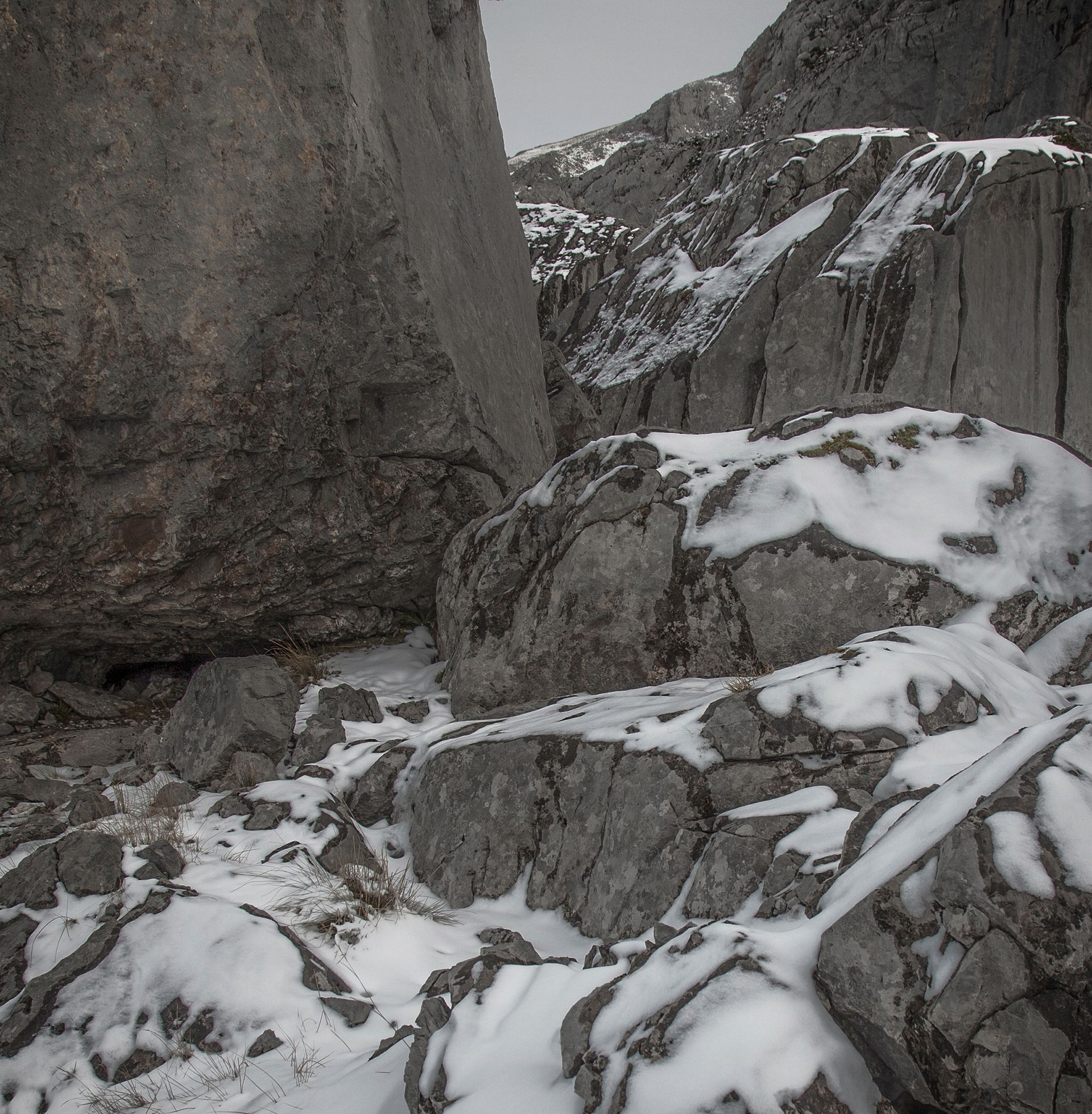 Escena de montaña nevada: grandes rocas grises y cantos rodados cubiertos de nieve.