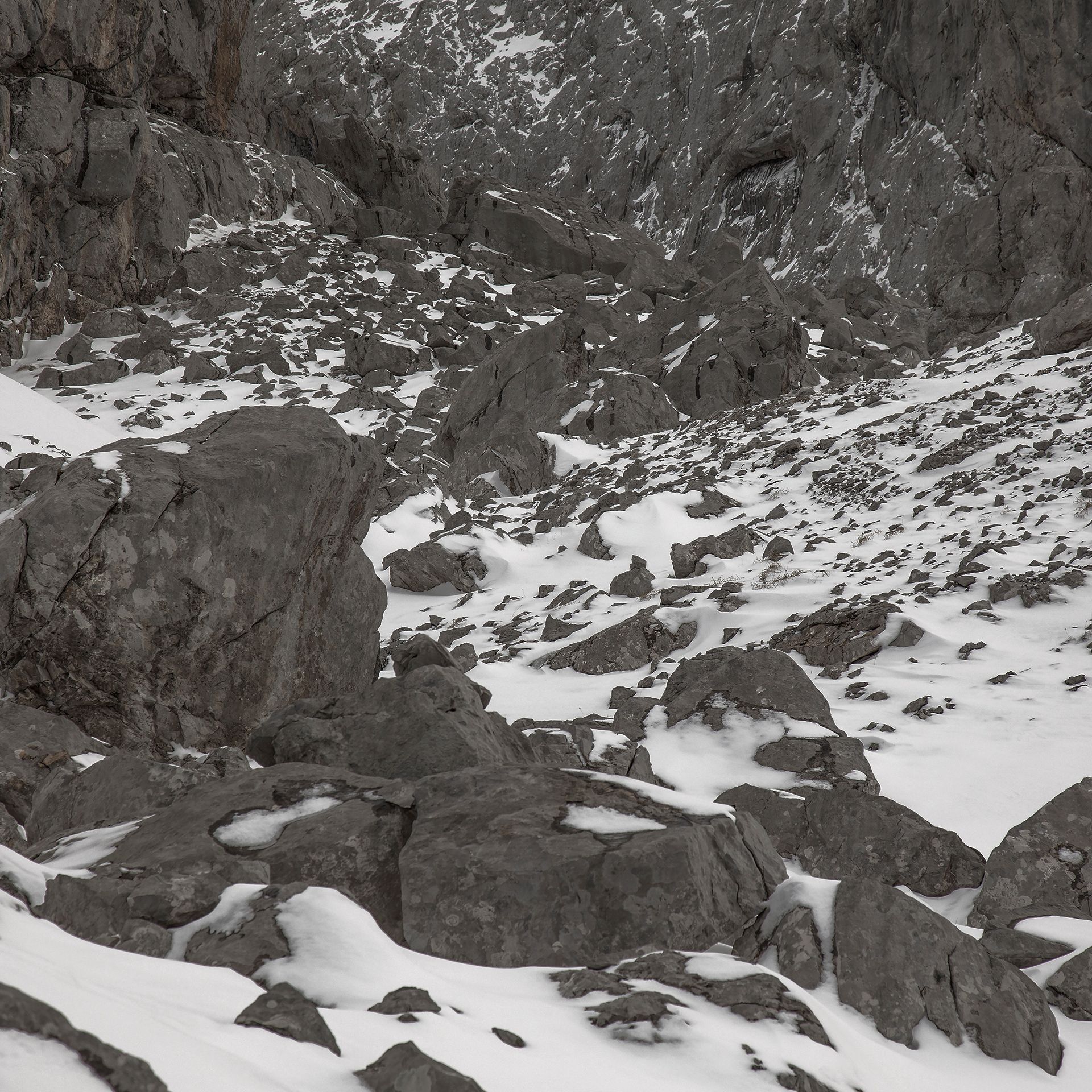 Paisaje de montaña rocosa con manchas de nieve.