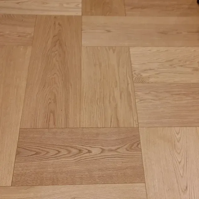 Un primer plano de un piso de madera con patrón de espiga.