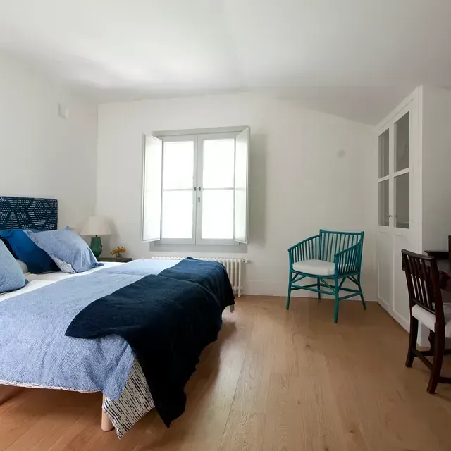 Un dormitorio con dos camas, una silla y un escritorio.