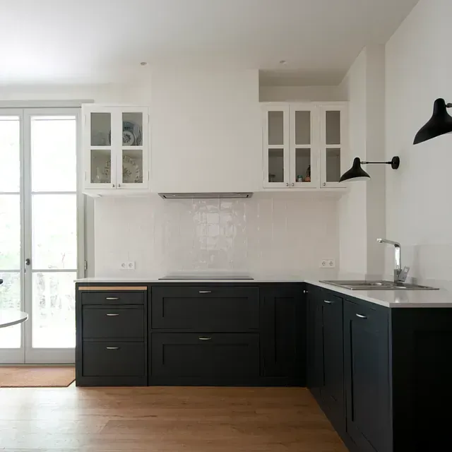 Una cocina con gabinetes negros, un fregadero y una ventana.