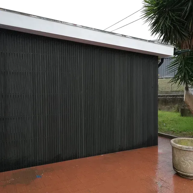 Una puerta de garaje negra con una planta en maceta delante de ella.