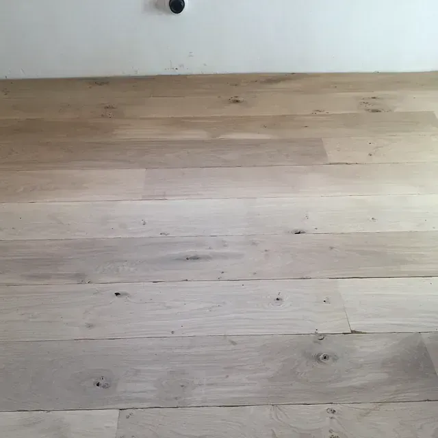 Un piso de madera en una habitación con una pared blanca.