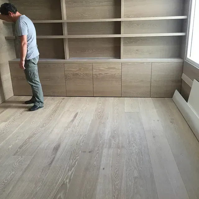 Un hombre está de pie en una habitación con estantes y armarios de madera.