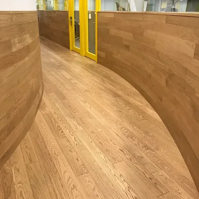 Un pasillo con suelo de madera y una puerta amarilla.