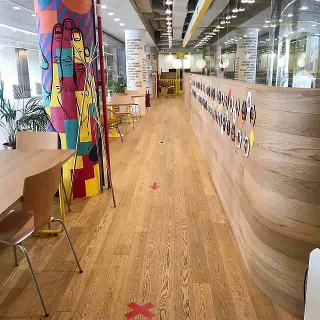 Un largo pasillo con suelos de madera, mesas y sillas.