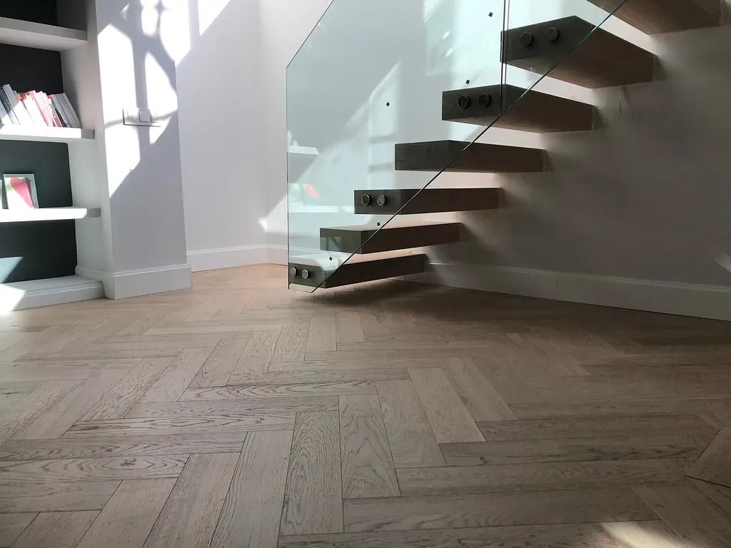 Una escalera de madera con barandilla de vidrio en una habitación.