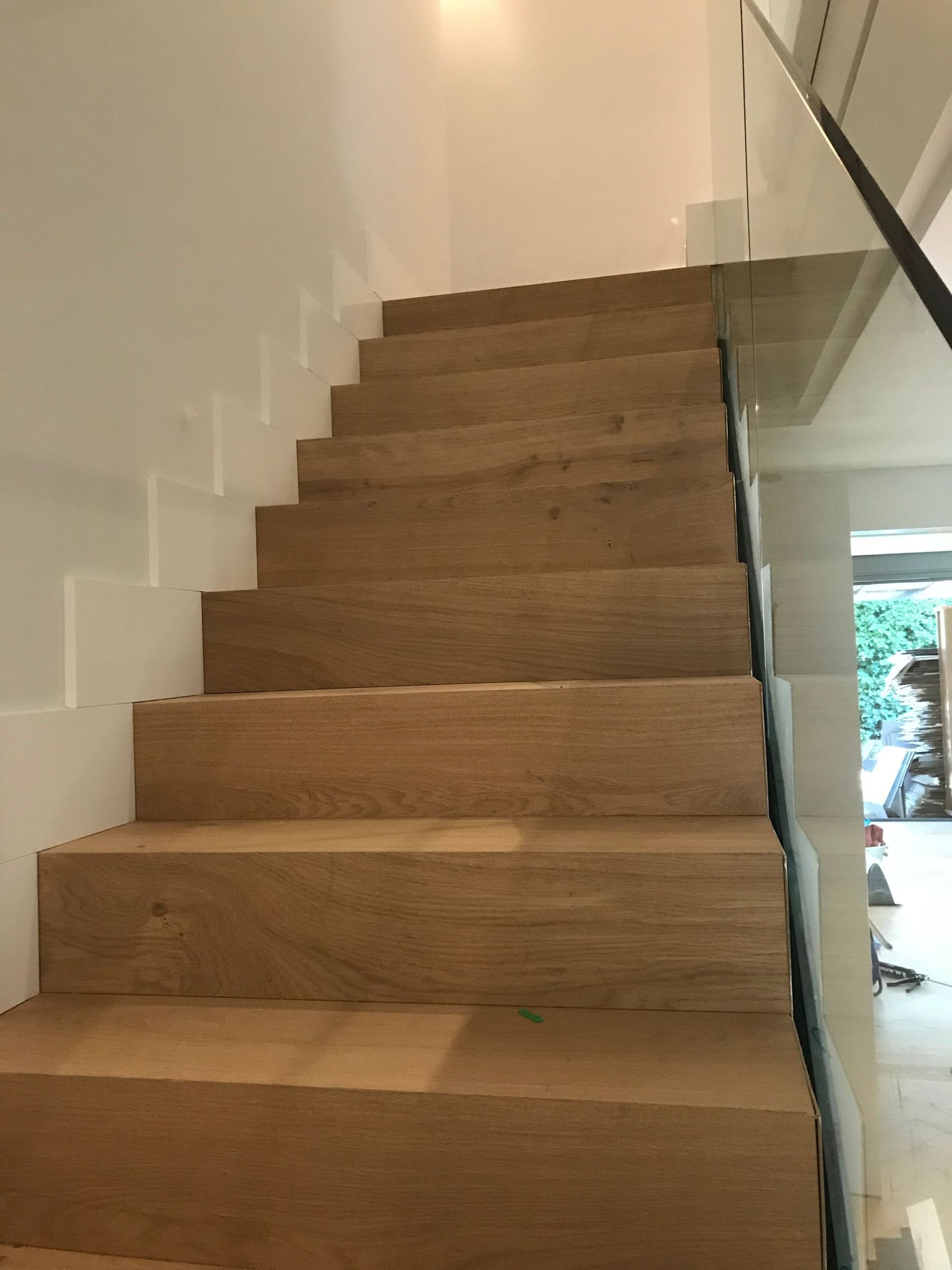 Una escalera de madera con barandilla de cristal en una casa.