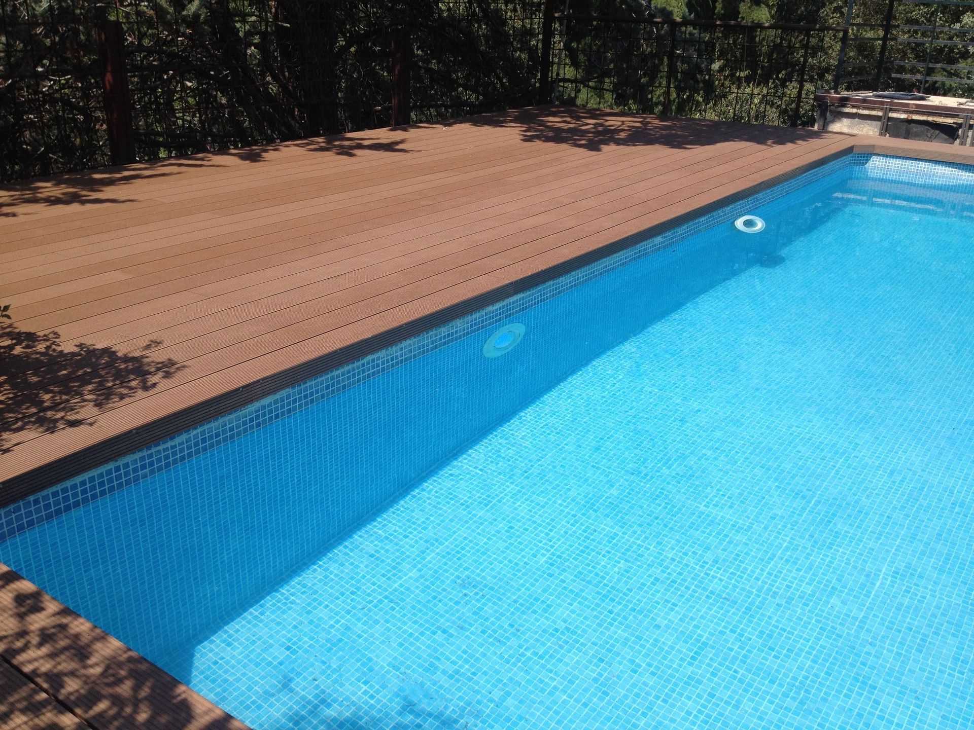 Una gran piscina con una plataforma de madera que la rodea.