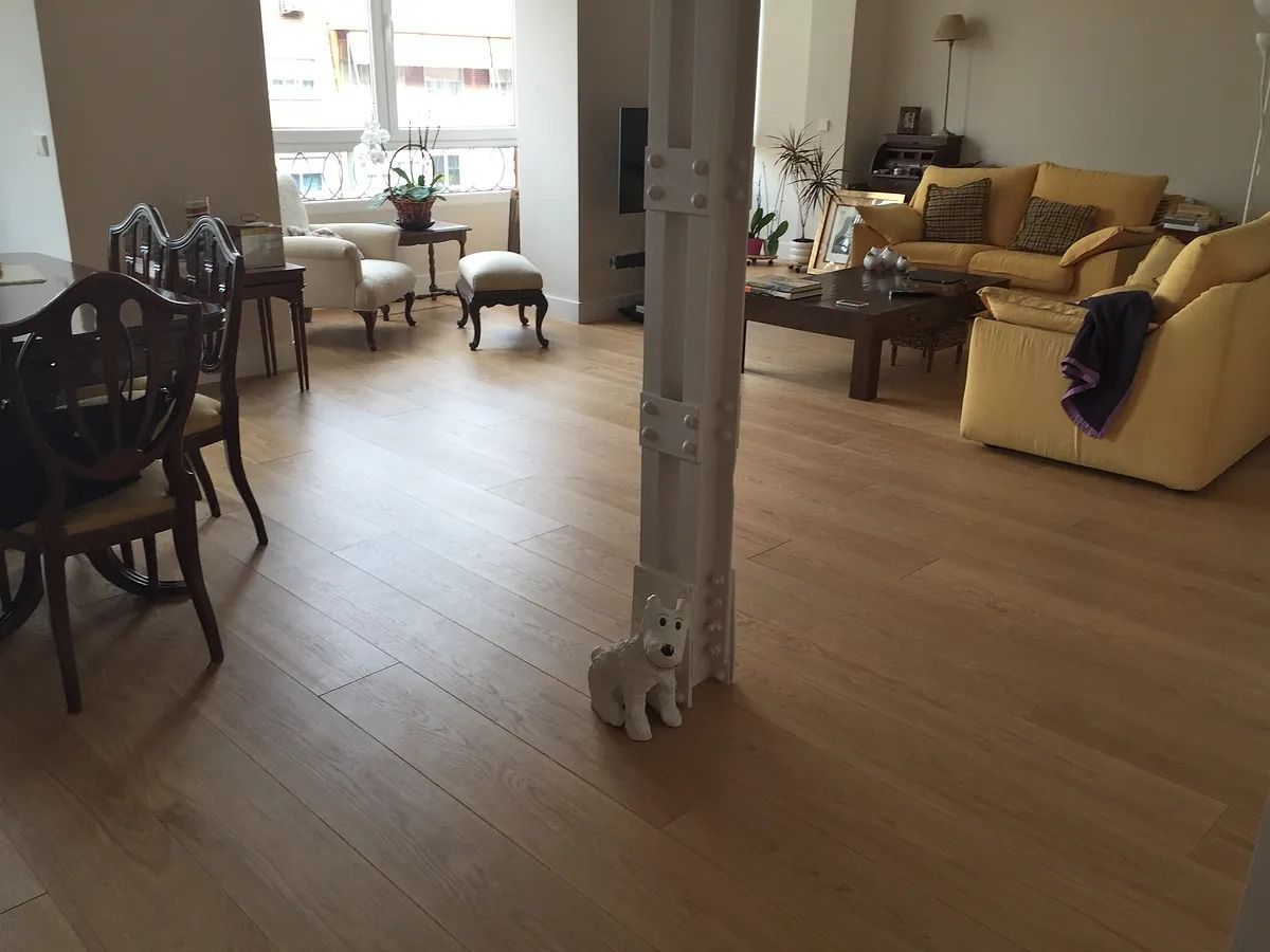 Una sala de estar con un sofá, sillas, una mesa y un perro en el suelo.
