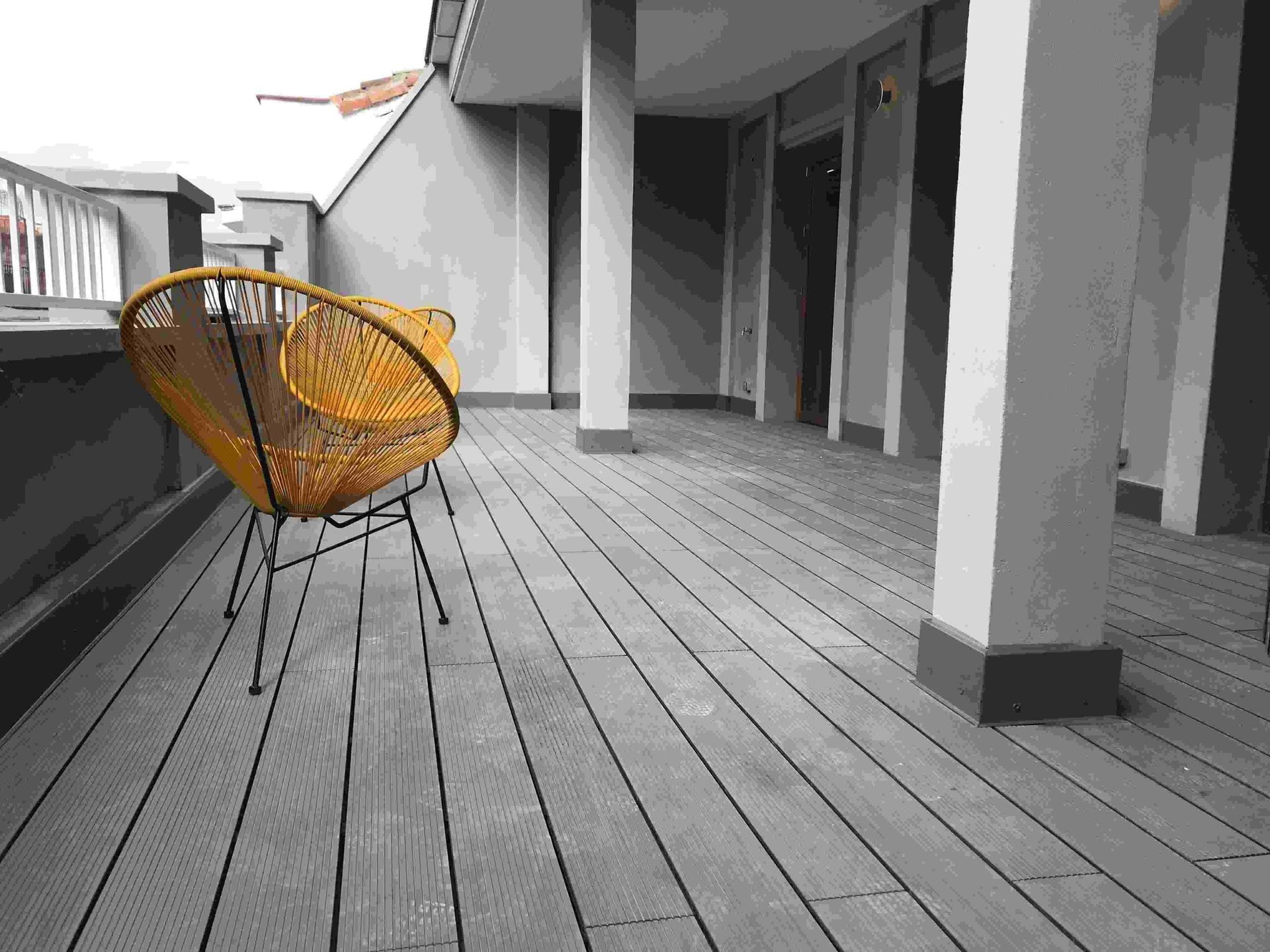 Una silla amarilla está sentada sobre una terraza de madera.