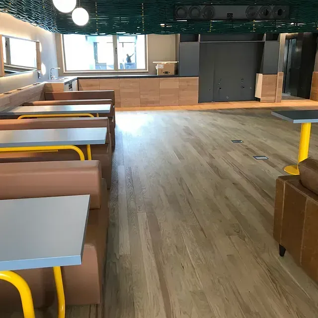 Un restaurante con suelos de madera, mesas y sillas.