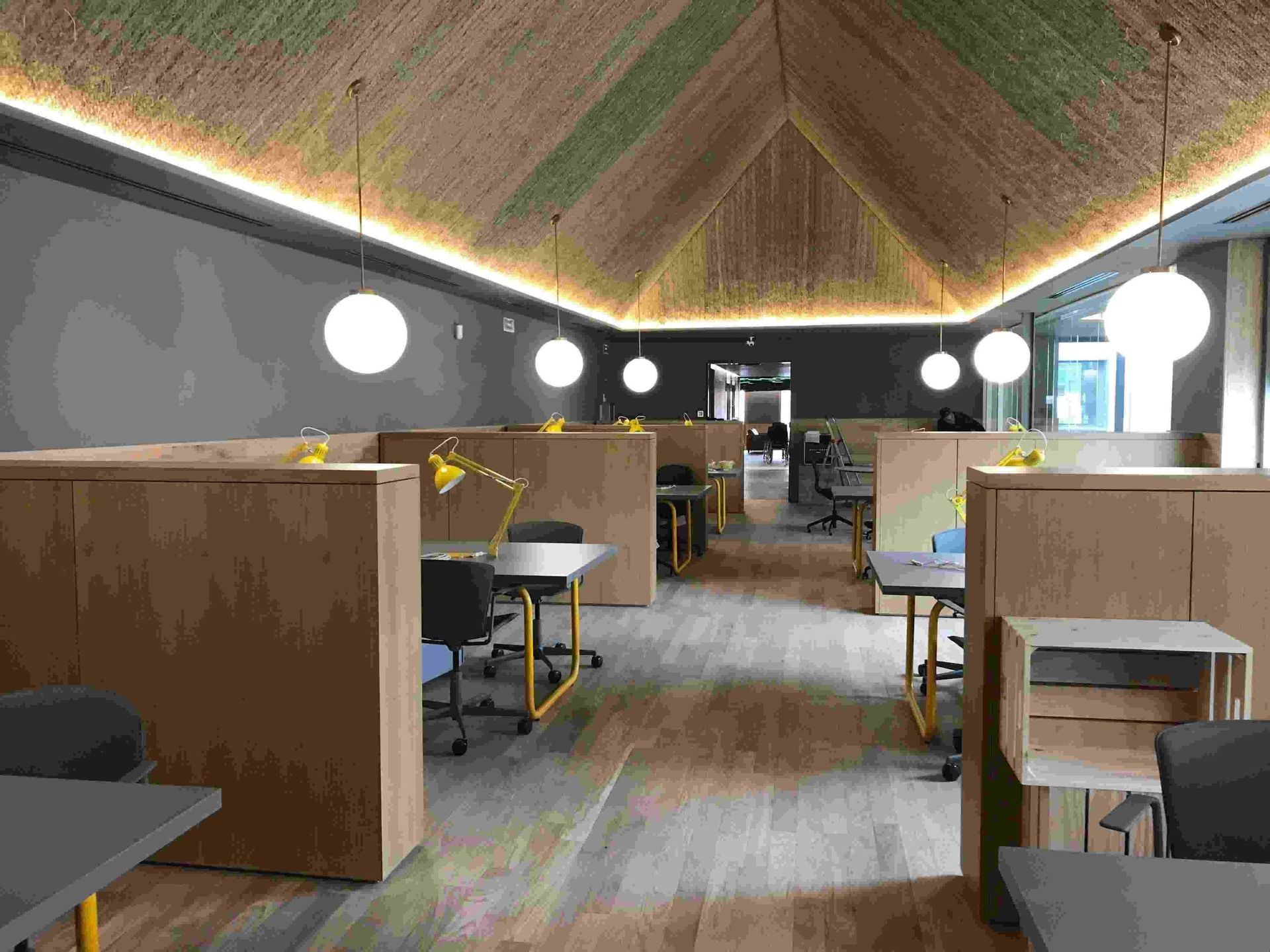 Una habitación grande con techo abovedado y cubículos con escritorios y sillas.