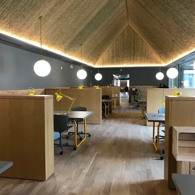 Una habitación grande con suelo de madera, mesas y sillas.