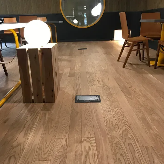 Un piso de madera en una habitación con sillas y mesas.
