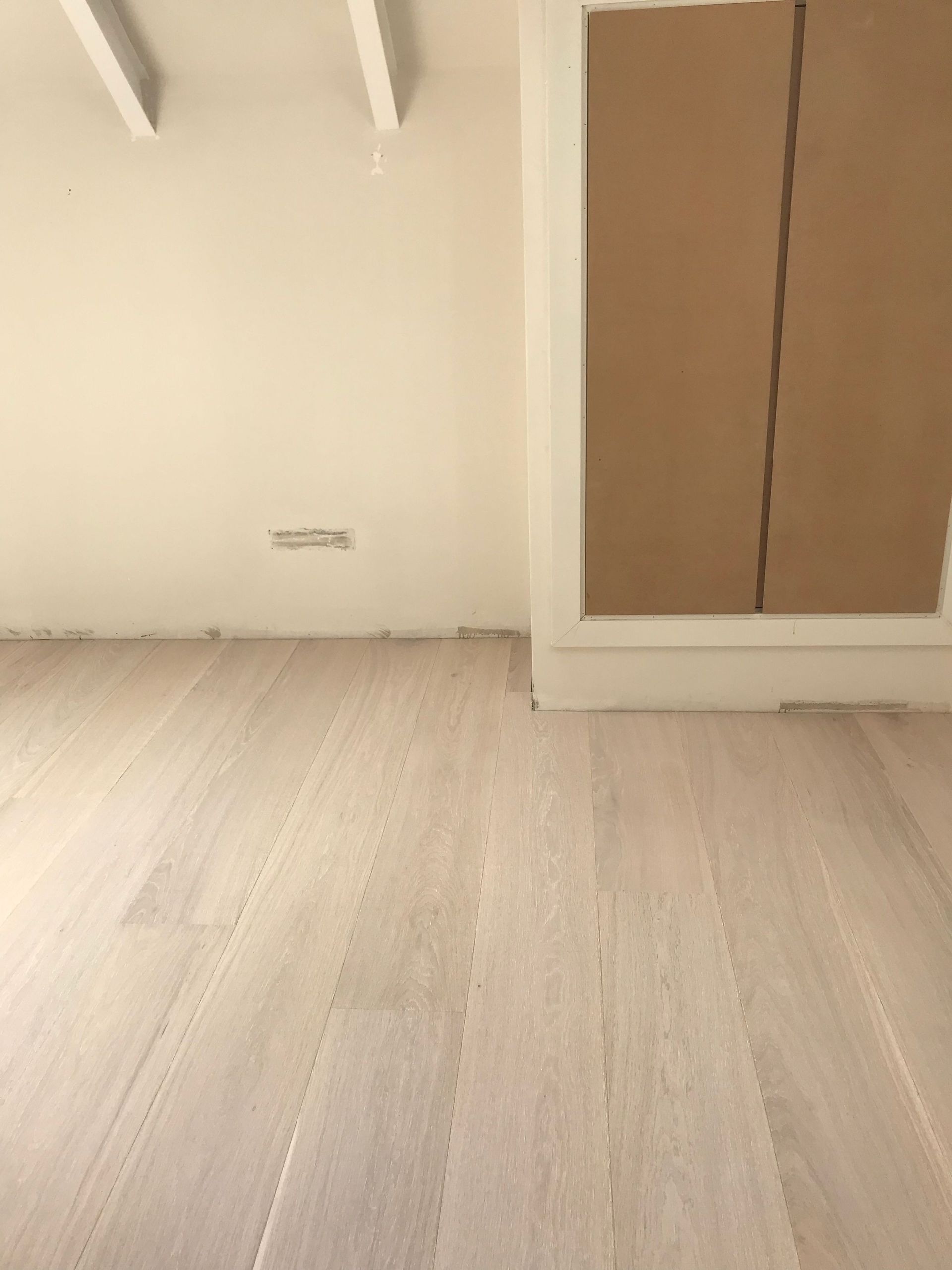 Una habitación con suelo de madera y paredes blancas.