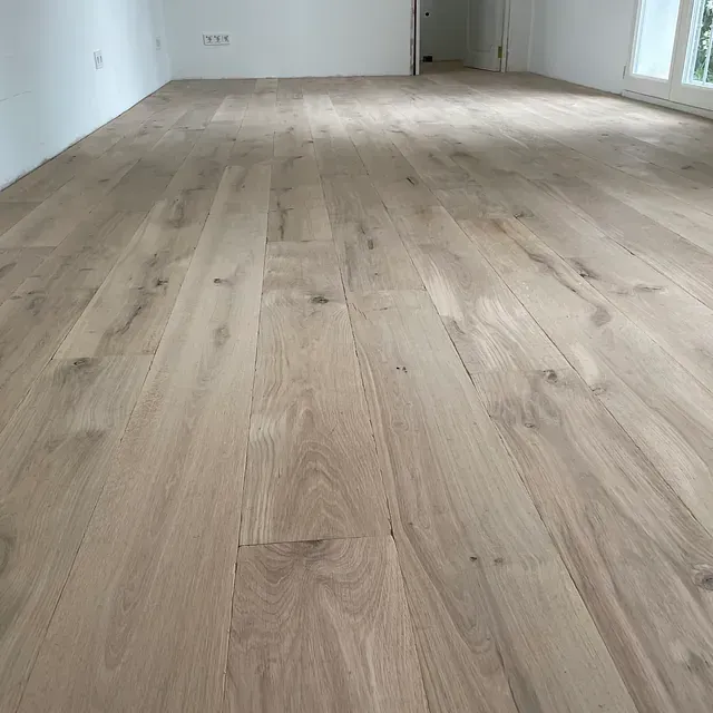Una habitación grande con suelo de madera y paredes blancas.
